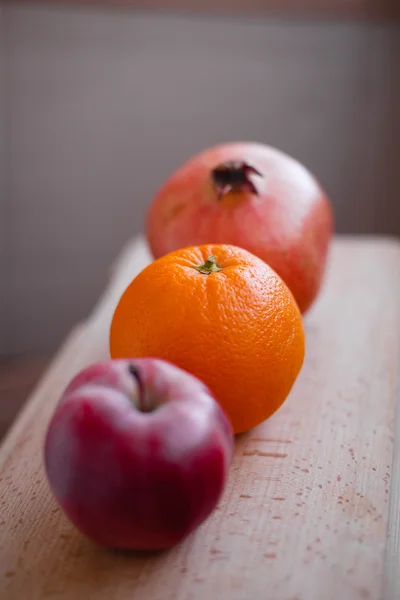 Healthy lifestyle. Healthy food. Proper nutrition. Fruit plate. Useful vitamins food. Apple, orange and pomegranate on a wooden table on light brown background