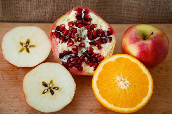 Healthy lifestyle. Healthy food. Proper nutrition. Fruit plate. Useful vitamins food. Apple, orange and pomegranate sliced on a wooden table on light brown background