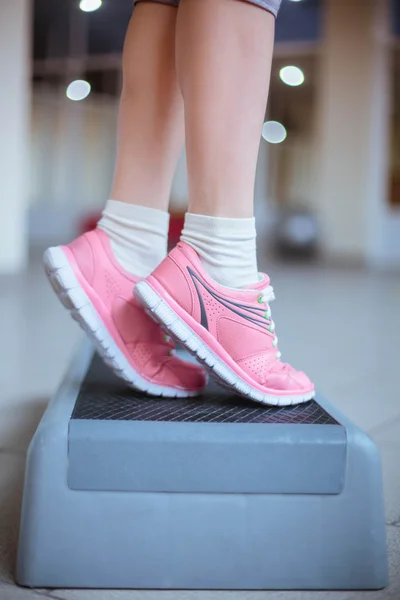 healthy lifestyle. slender legs of the young girl in a pink sports shoes on a step platform