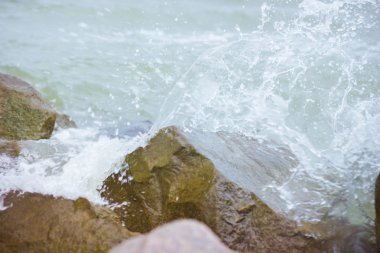 Denizde rüzgarlı ve soğuk hava. Deniz dalgaları buzlu. Deniz sprey ve köpük. Büyük ıslak taşlar
