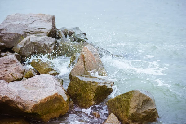 Temps venteux et froid en mer. Des vagues de mer sur les rochers. Spray marin et mousse. Grandes pierres humides — Photo