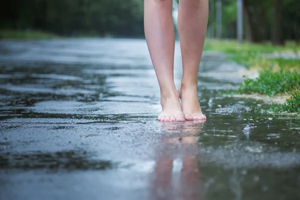 Joven chica hermosa caminando en el parque en el verano lluvia caliente descalzo a través de los charcos. Diviértete y disfruta. Lluvia cayendo. Gotas de lluvia. Ropa mojada — Foto de Stock