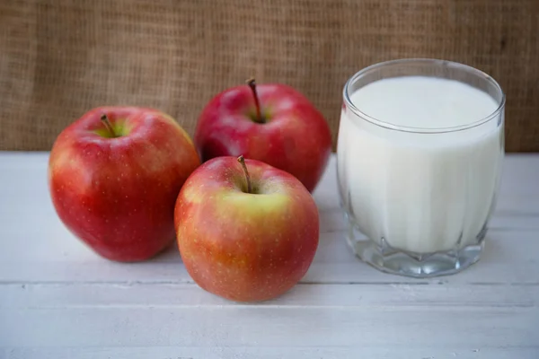 Healthy lifestyle. Useful vitamins food. Proper nutrition. Fruit plate. Apple yogurt diet. Red ripe apples and a cup of yogurt on a wooden table on a light brown background
