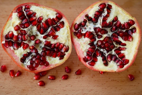 Healthy lifestyle.  Healthy food. Proper nutrition. Fruit plate.Useful vitamins food. Vegetarian food. Fruit diet. Two halves of a ripe pomegranate on a wooden table on light brown background. cut pomegranate with seeds