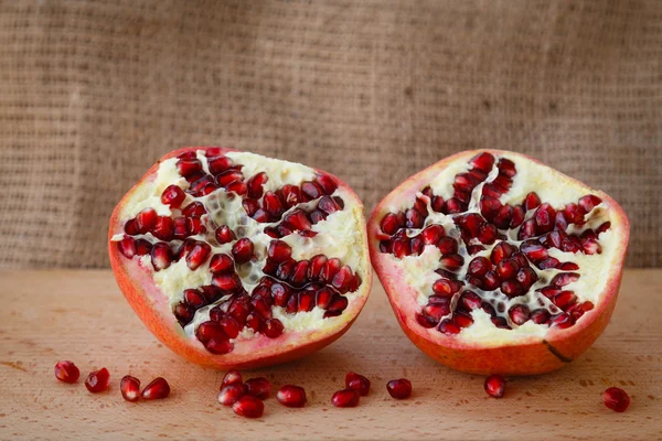 Healthy lifestyle.  Healthy food. Proper nutrition. Fruit plate. Useful vitamins food. Vegetarian food. Fruit diet. Two halves of a ripe pomegranate on a wooden table on light brown background. cut pomegranate with seeds