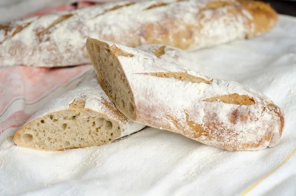 Baguette tagliato a metà su tessuto bianco — Foto Stock