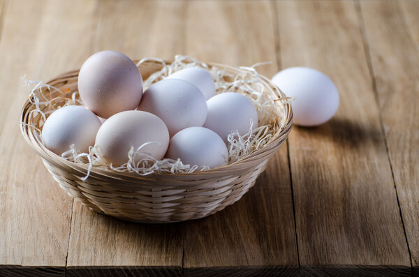 eggs in a rustic wicker basket on wooden table