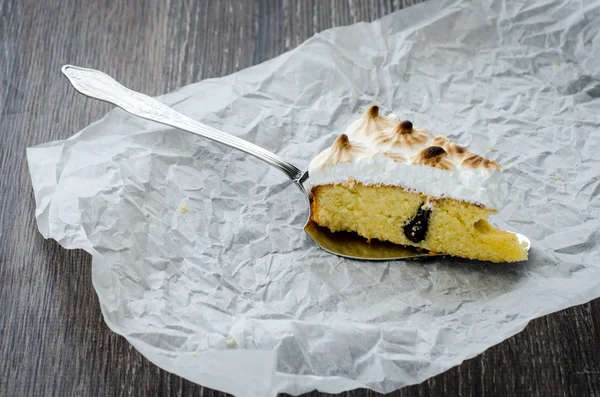 Un pezzo di torta di bretone con prugne e meringa su un tavolo di legno — Foto Stock