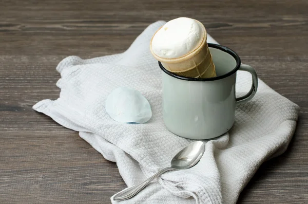 Cono de helado en una taza de esmalte sobre una mesa de madera — Foto de Stock
