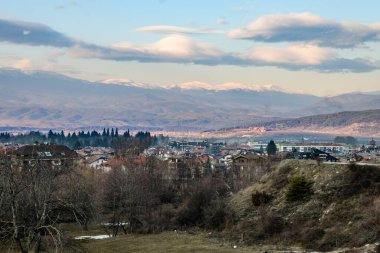 Bansko şehrinin geniş, karla kaplı Pirin dağ sırasının dramatik bir bulutun altında yer aldığı bir vadiye yerleşmiş geniş bir panorama..