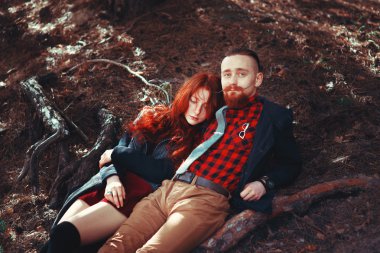 Kızıl saçlı adam, sakallı ve kıvırcık kızıl saçlı kız doğanın muhteşem manzarasının arka planında. Ormanda yürüyüşe çıkmış güzel bir çift..