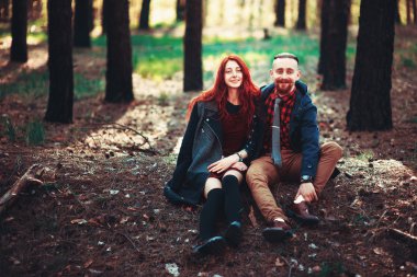 Kızıl saçlı adam, sakallı ve kıvırcık kızıl saçlı kız doğanın muhteşem manzarasının arka planında. Ormanda yürüyüşe çıkmış güzel bir çift..