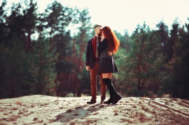 Kızıl saçlı adam, sakallı ve kıvırcık kızıl saçlı kız doğanın muhteşem manzarasının arka planında. Ormanda yürüyüşe çıkmış güzel bir çift..