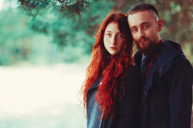 Kızıl saçlı adam, sakallı ve kıvırcık kızıl saçlı kız doğanın muhteşem manzarasının arka planında. Ormanda yürüyüşe çıkmış güzel bir çift..