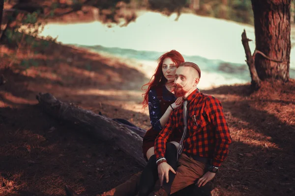 The red-haired guy with a beard and curly red-haired girl on the background of fabulous scenery of nature. Beautiful loving couple on a walk in the woods.