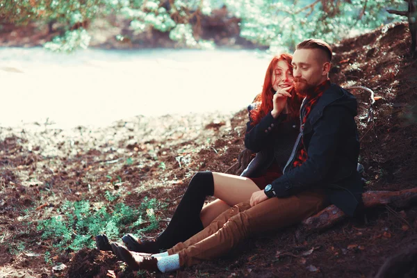 The red-haired guy with a beard and curly red-haired girl on the background of fabulous scenery of nature. Beautiful loving couple on a walk in the woods.