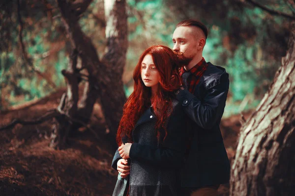 The red-haired guy with a beard and curly red-haired girl on the background of fabulous scenery of nature. Beautiful loving couple on a walk in the woods.
