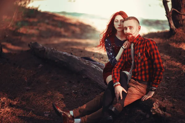 The red-haired guy with a beard and curly red-haired girl on the background of fabulous scenery of nature. Beautiful loving couple on a walk in the woods.