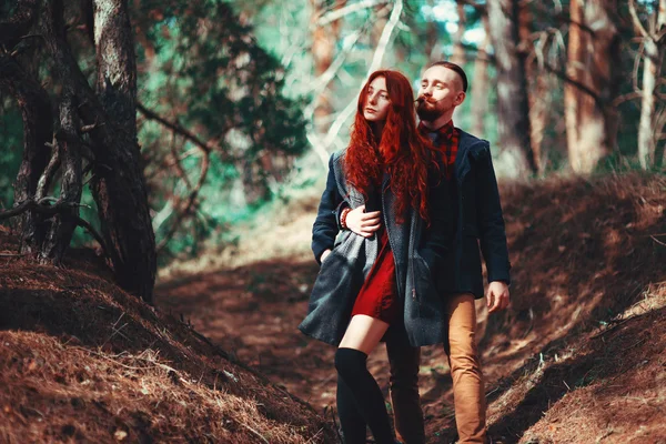 自然の素晴らしい景色を背景に 髭と巻き毛の少女を持つ赤い髪の男 森の中を歩く美しい恋人たち ロイヤリティフリーのストック写真