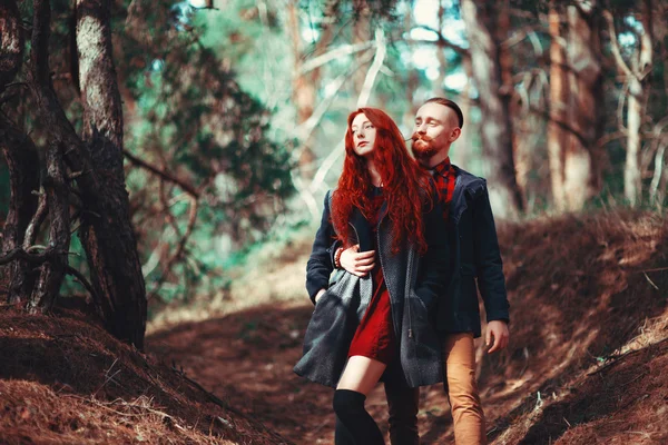 自然の素晴らしい景色を背景に 髭と巻き毛の少女を持つ赤い髪の男 森の中を歩く美しい恋人たち ストック写真
