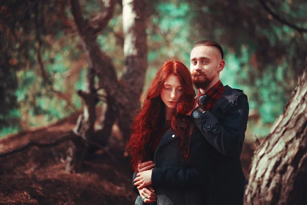 自然の素晴らしい景色を背景に 髭と巻き毛の少女を持つ赤い髪の男 森の中を歩く美しい恋人たち ロイヤリティフリーのストック画像