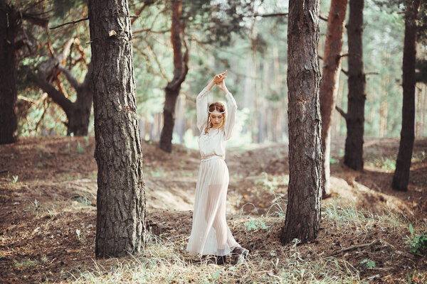 Beautiful artistic photo ginger girl in white dress walking in forest.