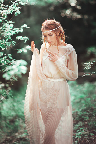 Beautiful artistic photo portrait of a mysterious girl in white dress in the woods