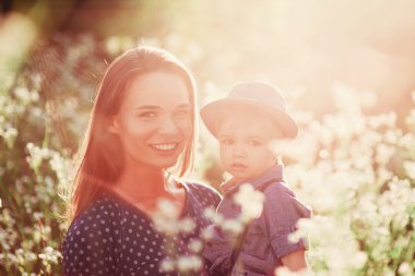 Sevgi dolu bir anne oğlunu kollarında tutuyor, onunla oynuyor ve ona sarılıyor. Aile doğada dinleniyor. yumuşak odak