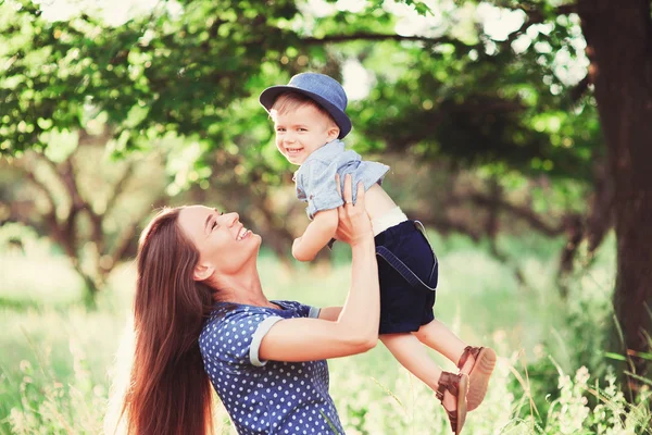 息子を抱いている母親を愛し 彼と遊び 彼を抱きしめる 家族は自然の中で休む ソフトフォーカス — ストック写真