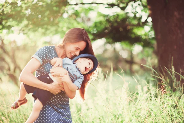 息子を抱いている母親を愛し 彼と遊び 彼を抱きしめる 家族は自然の中で休む ソフトフォーカス — ストック写真