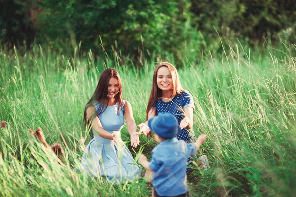 美しい幸せな家族は自然の中で休んでいます 公園で男の子と遊ぶ母親と叔母の2人の女性 ソフトフォーカス — ストック写真