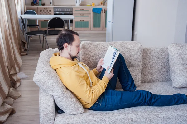 man reading a book on the couch