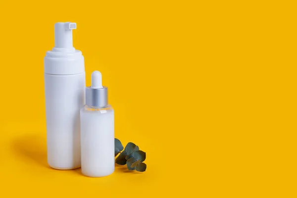 cosmetic bottles on yellow background with copy space
