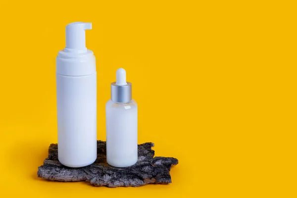 cosmetic bottles on yellow background with copy space