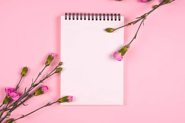 Blank sheet of paper on a pink background with flowers
