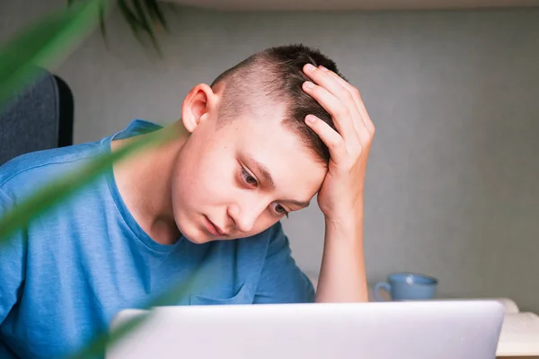 Teen boy tiredly looking at the computer screen