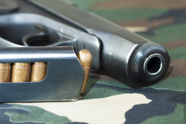 Pistola de arma de fogo e munição arma de mão em fundo camuflagem militar — Fotografia de Stock