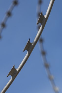 Dikenli tel tuğla duvarlar boyunca uzanan