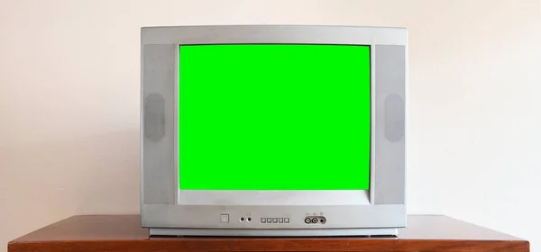 Modası geçmiş, boş yeşil ekranlı gümüş renkli bir televizyon 1990 'lardaki bir apartman dairesinde antika bir masada oturuyor..
