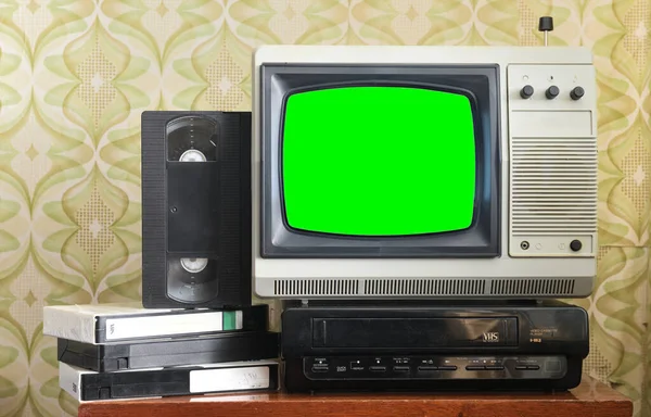Ekrana yeni görüntüler eklemek için yeşil ekranlı eski gümüş renkli televizyon, duvar kağıdı arka planında VCR.