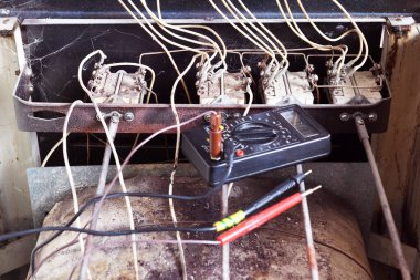 Profesyonel elektrikçi çoklu sayaçla elektrikli ocağı yakıyor. Bir apartman dairesinde çekilmiş. Eski bir elektrikli ocağın tamiri..