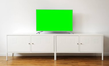 Geniş ekran yeşil ekran TV, beyaz bir duvara karşı krom bir ayakta duran metin ve video için..