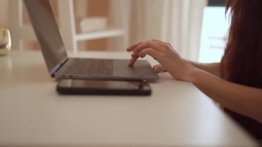 Güzel organize edilmiş bir çalışma alanında, odaklanmış bir kadın, etkili ve üretken çalışma alışkanlıklarıyla modern teknolojiyi kusursuz bir şekilde harmanlayarak, zarif ve sofistike dizüstü bilgisayarına yazı yazar.