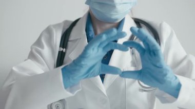 Laboratuvarda, laboratuvar önlüğü ve eldivenleriyle kendini adamış bir sağlık uzmanı kalbi elleriyle şekillendirir, tıpta hayati önem taşıyan şefkati sembolize eder, başkalarına özen göstererek onlara ilham verir.