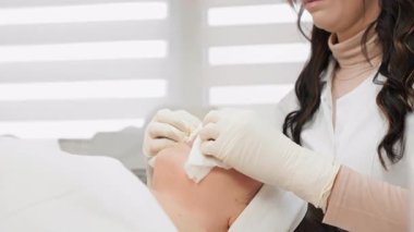 Yetenekli bir kozmetolog, huzurlu bir klinikteki değerli bir müşteriye derin bir rahatlatıcı cilt bakımı sunarak profesyonel cilt bakımının güzellik ve refah için önemini vurgular.