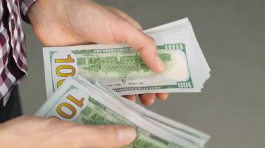 Bu yakın çekim, ABD para birimlerini idare etme ve finans, iş ve günlük işlemlerin temaları ile ilgili dokunsal deneyimlerin altını çizerek, yığınla parayı sayan elleri gösteriyor.