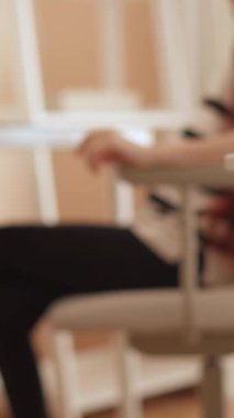 Genç bir kadın şık bir çalışma alanında oturuyor, dizüstü bilgisayarına odaklanmış. Doğal ışık odayı sarıyor, sakin ve üretken bir atmosferi vurguluyor. Dekoratif bir bitki ayarları güçlendirir.