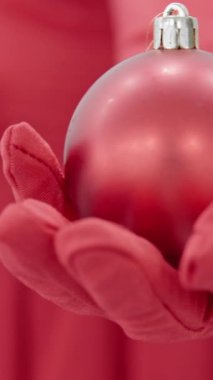 Yakın plan, parlak kırmızı eldivenli, iyi manikürlü bir eli, parlak kırmızı bir Noel aksesuarı tutarken, Noel ruhunun neşeli özünü güzel bir şekilde yakalıyor ve sezonluk neşe saçan