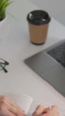 Üretken bir öğrenme ortamında, odaklanmış bir öğrenci, yaratıcı çalışma alanlarını ve konsantrasyonlarını artıran canlı yeşil bir bitki ile kahveyi yudumlarken laptopuna notlar alır.