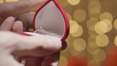 Kırmızı kadife bir yüzük, göz alıcı bir nişan yüzüğünü ortaya çıkarmak için açılır. Romantik bir zemin üzerinde parıldar. Bu zemin, iki bireyin hayat yolculuklarına başladıkları aşkın ve bağlılığın simgesidir.